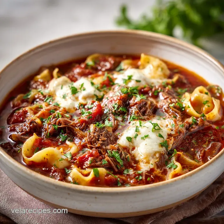 A rustic bowl of hearty red soup topped with melted mozzarella and fresh basil beside a crisp piece of garlic toast.